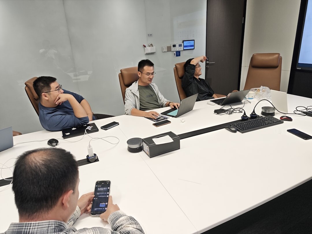 Business team collaborating around conference table with laptops